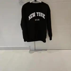 En svart crewneck tröja med vit text  New york  Är S men passar även M