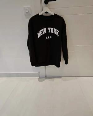 En svart crewneck tröja med vit text  New york  Är S men passar även M