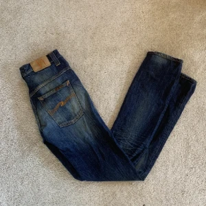 Riktigt snygga Nudiejeans 30/34 - Nudiejeans i modellen Thin Finn, väldigt bra skick förutom en liten slitning på vänster framsida! (Syns knappt) || Modell: Thin Finn || Skick: 8/10 || Sorlek: W30/L34 ||Passform: Vanliga/tight || Nypris: 1200  Frågor och funderingar? Hör gärna av dig