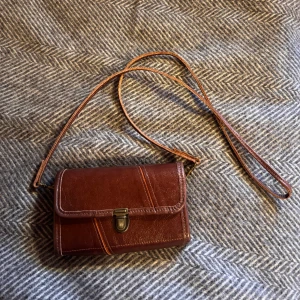 Fin läderväska - Aldrig använd. Köpt från lokal hantverkare för 800 kr. Fin äkta läderväska. Ca mått, längd: 20 cm höjd: 12 cm och djup: 5 cm
