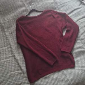 En mörkröd stickad tröja med öppning i ryggen. Använd 2-3 gånger. Långa ärmar och avslappnad passform. 