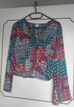 Topp - Färglad topp med trumpet ärmar. Storlek 34