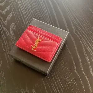 Säljer min YSL korthållare inköpt 2021! Den är röd och är riktigt cool, säljer den då jag inte använder den. Box medföljer & den är såklart äkta, kvitto finns! Köpt för 3000!  Finns två skador på varje kant högst uppe på korthållare som knappt syns. 