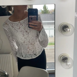 Vit spetstopp - Vit långärmad topp i blommig spets från GinaTricot. Ärmarna har slits, knapp i nacken.