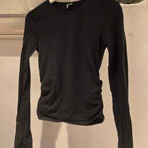 Långärmad tröja i svart från nelly trend (nelly.com). Schrunch-detaljer på sidorna samt en längre slits på ärmarna. Fint skick.