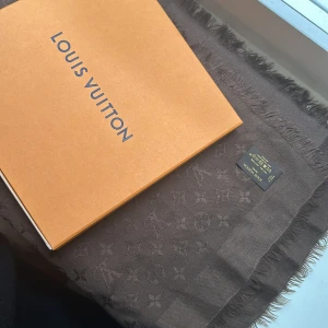 Louise Vuitton monogram sjal brun Icon - 142.5 x 142.5 cm (Length x Height) Brown 60% silk, 40% wool Jacquard weave Monogram pattern Woven Louis Vuitton signature Fringe finish Dry clean only  Använd men i bra skick