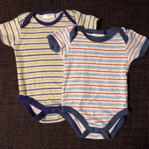 2 kortärmade bodys strl. 62 - 2 kortärmade bodys med ränder i storlek 3-6 månader (upp till 8 kg, 62 cm). Något blekare än nya, samt "tvättluddiga". Inga hål eller fläckar.   Tvättade i parfymfritt tvättmedel och utan sköljmedel