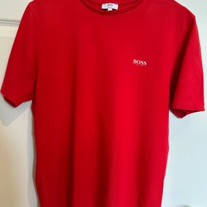 T-shirt Boss, röd - Röd T-shirt från Hugo Boss. Storlek 16 år/xs i vuxen.