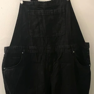 HÄNGSELBYXOR  - Hängselbyxor svart stentvättade i jeans material, med silver detaljer. Strl. XXL Normal/ mindre i storleken. Aldrig använda endast testad.