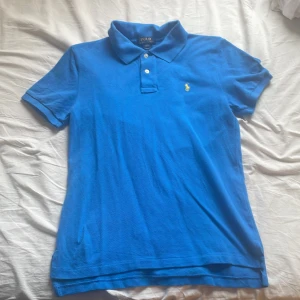 Blå Ralph Lauren piké - En blå Ralph Lauren piké med gult märke. Storlek L i barnstorlek, men passar mig som vanligtvis har storlek XS-S. Inga defekter eller fläckar🥰 Hör av er för fler bilder/ frågor!