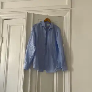 Superfin linneskjorta från Massimo Dutti i ett blått och vitt rutigt mönster.  Skjortan är i storlek L och personen på bilden är 188cm.   I fint använt skick utan defekter. 