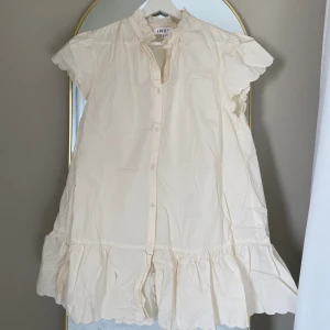 Fin sommarklänning  - Använd en gång vid konfirmation. Jättefin i cremevit, slutsåld. Med räffling nertill, vid ärmarna och kragen. Nypris 800kr