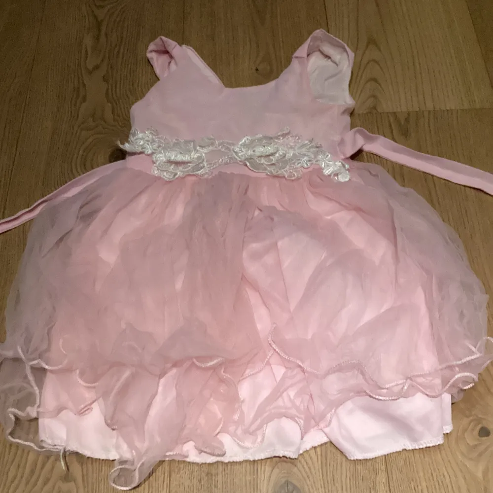 En rosa finklänning för barn med ros detaljer men även snören att knyta där bak. Fint skick.. Klänningar.