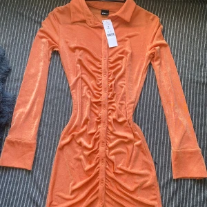 Kläning - Klänning som är skimrig. Aldrig använd. Lite genomskinlig  Mer korall än orange 