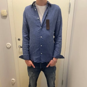 Riley Linneskjorta från Brothers - Säljer min helt nya Linneskjorta från Riley  100% linne i materialet och skjortan är helt ny med prislappen kvar. Linneksjortan är köpt från Brothers. Nypris är runt 700-800. Storlek S, modellen på bilden är ca 180. Hör av er vid intresse!