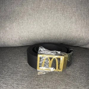 McDonald’s Bälte - Storleken är justerbar i och med låset där man kan klippa i bältet.  Skick: 5/5 (Oanvänt i påsen jag fick den i) Färg: Svart/Guld