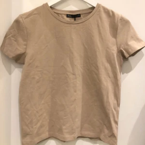 Beige t-shirt - Beige t-shirt ifrån Zara i storlek S, i nyskick med prislapp kvar! Fler bilder kan skickas vid behov! 