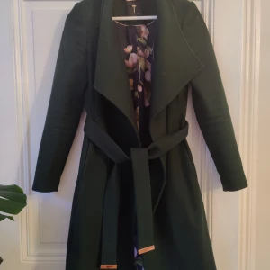 Ted Baker ullkappa - Superfin och varm mörk grön Ted Baker ullkappa (75% ull, 5% cashmere) i storlek 1 (motsvarar 34/36). Rosaguld detaljer och blommönster i fodret. Bra skick.