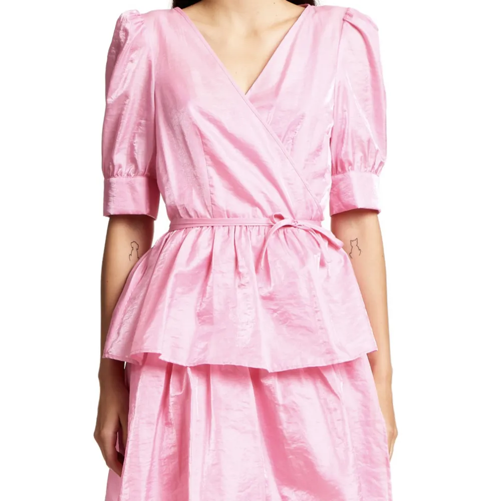 Helt oanvänd, fin rosa kortare klänning med knyte omlott i midjan. Fint skimrande tyg, med underklänning i. Nypris :1900kr.. Klänningar.