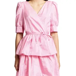 Helt oanvänd, fin rosa kortare klänning med knyte omlott i midjan. Fint skimrande tyg, med underklänning i. Nypris :1900kr.