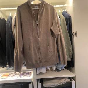 Säljer en helt ny John Henric 100% Kashmir zip med luva, i strl medium, beige. Aldrig använd, skick 10/10. Nypris 2500 kr