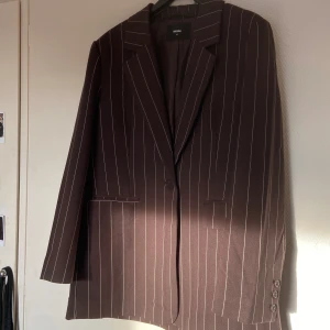 Oversized brun kavaj med lodräta vita linjer - Säljer min jätte fina bruna kavaj som är oversized i storlek M och köptes från Bik Bok, då den inte längre kommer till användning 