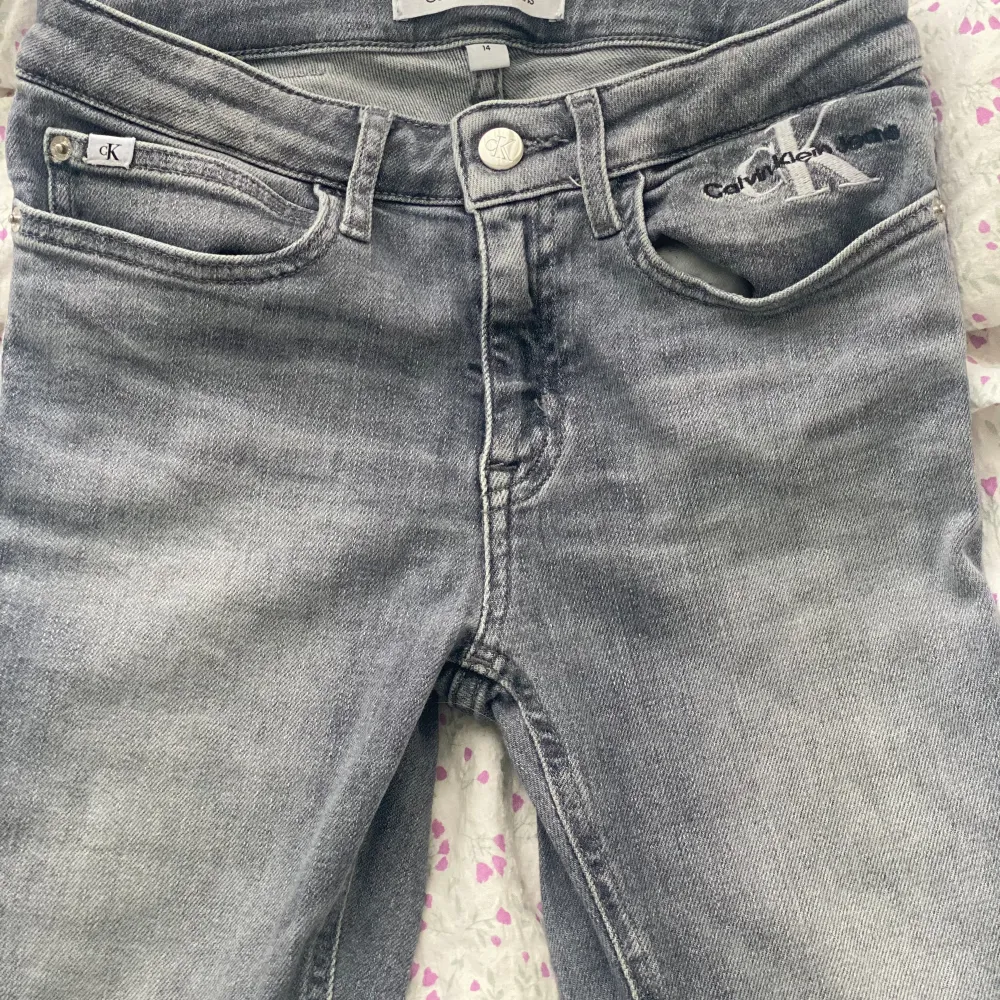 Jätte snygga gråa Calvin Klein jeans, low/mid waisted, strl 14/158/164. Jätte fint skick, säljer pga att dem blivit för korta. Nypris 799kr.⭐️  Köparen står för frakten.. Jeans & Byxor.