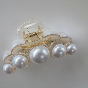 Hårklämma med pärlor - En elegant hårklämma med stora vita pärlor. Klämman är genomskinlig med en guldfärgad fjädermekanism, aldrig använt 