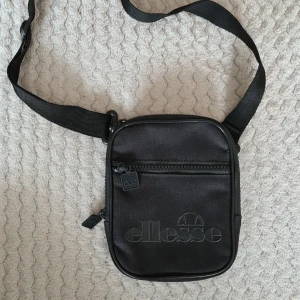 Ellesse Man purse, mobilväska svart - Ellesse mobilväska i svart mått: Höjd: 175 mm. Bredd: 145 mm. Nyskick, inköpt på Zalando med frakt för 350:-.