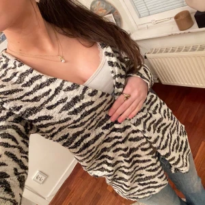 Zebra tröja - Så cool kofta från gina med zebra mönster. De svarta delarna har lite glitter i sig. Man kan sätta fast tröjan med ett örhänge eller en säkerhetsnål om man vill ha den stängd💗