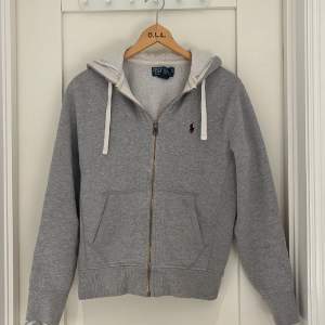 Hej, säljer en snygg Ralph Lauren zip hoodie i färgen grå samt storleken XS. Skick 8/10 sparsamt använd, annars inga problem. Kom dom för fler bilder/frågor osv!🙌🏻