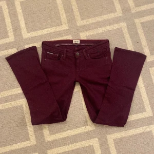 Lågmidjade vinröda/lilaaktiga jeans - Jättesnygga lågmidjade jeans i vinröd/lila färg från Tommy Hilfiger. Tyvärr passar de inte lig, därav förra säljarens bilder. Endast testade av mig, men i nyskick annars.