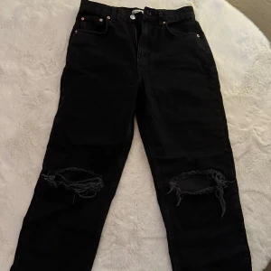 Raka svarta jeans - Ett par raka jeans med hög midja i storlek 38. De har hål på båda knäna och är knappt använda! Jag är villig att diskutera pris🤩 ordinarie pris var 600kr