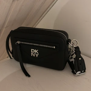 Dkny väska  - En väska som jag fick i julklapp, är inte så intresserad av väskor. Den är helt ny! Har kollat upp pris på DKNY VÄSKOR då priserna ligger på 900-1500kr. Mitt pris går att diskuteras då jag vill bli av med väskan! 