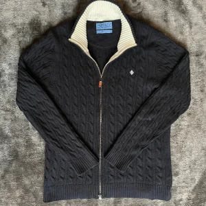 Morris fullzip - Säljer min skitsnygga Morris fullzip storlek M som är nyskick. Den är kabelstickad med väldigt mörkblå o vit i insidan och toppkvalitet. Äkta solklart:) !pris e fast!