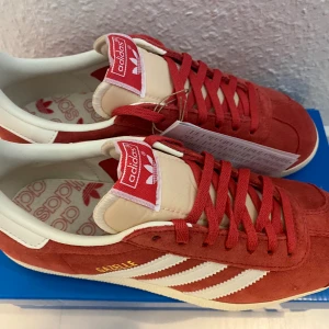 Nya röda Adidas Gazelle - storlek 36 2/3 - Adidas Originals Gazelle Färg: Röd och krämvit (Glory Red/off White/cream White) Obs storlek 36 2/3 (normal i storlek) Innermått är 23,7 cm Nya och oanvända. Slutsålda direkt. 