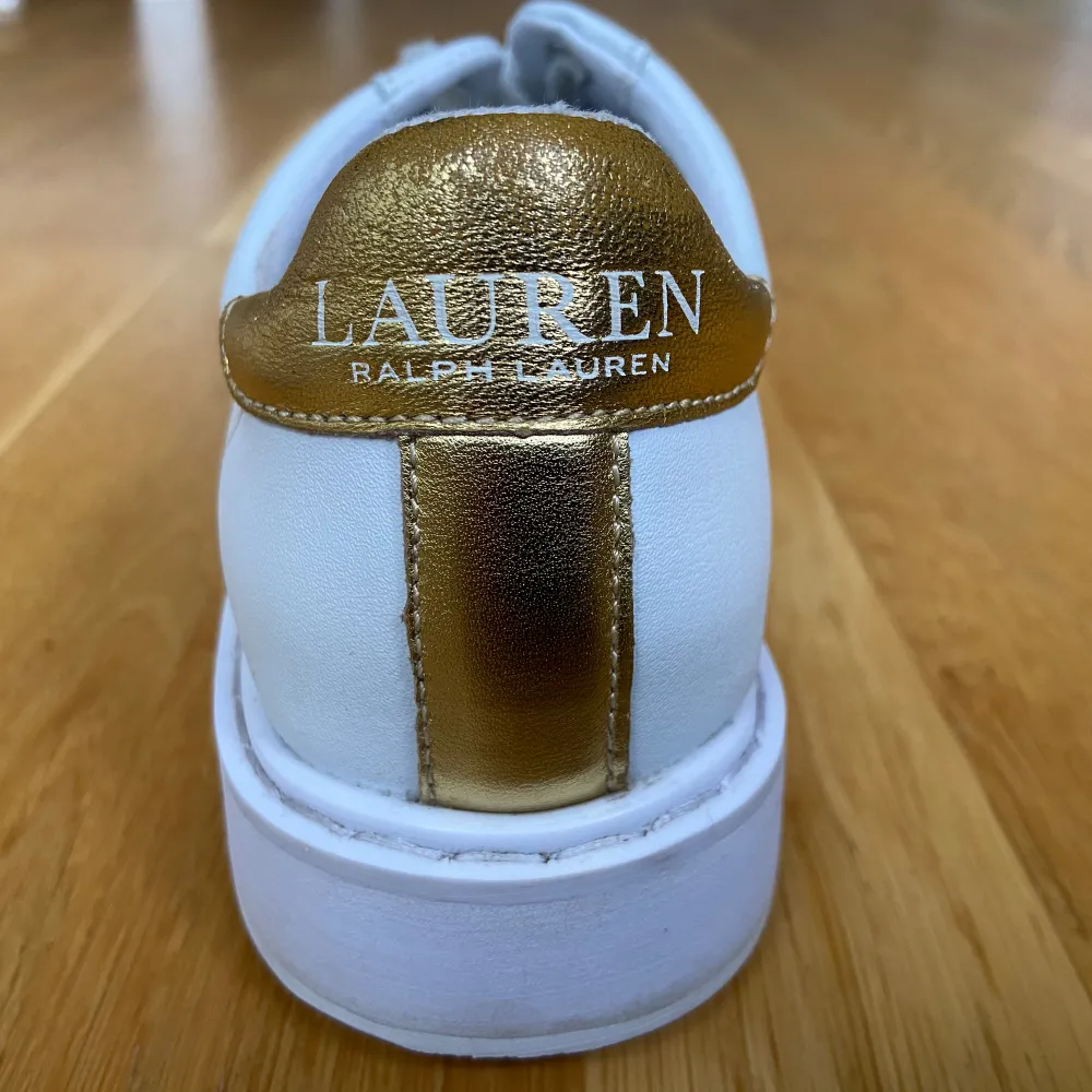 Säljer ett par vita och guldiga Ralph Lauren skor som är storlek 35.5. Den är bara använd tre gånger och har inga defekter.. Skor.