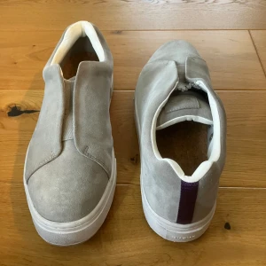 Herrskor från EYTYS - Grå skor med lila detalj. Strl 45, innermått knappt 29cm. Använda endast ett fåtal gånger. Mycket fint skick. Insida av häl och innersulan i helt oskadat skick. Nypris 2000 kr. Säljes för 800 kr.