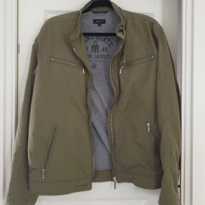 Gant State GNH 1949 Biker Jacket  - Snygg olivgrön Gant jacka i storlek L. Sparsamt använd så i mycket bra skick. Jackan är något stor och lång i ärmarna på mig (personen på bilderna). Jag har normalt storlek S eller M. Är 173 cm och väger 67 kg.