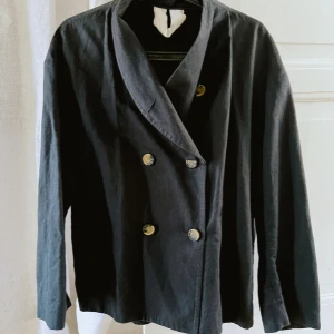Arket svart jacka trench  - Använd men i fint skick   Dubbelknäppt jacka i en blandning av linne och ekologisk bomull. Oversized passform med en något rundad silhuett. Fickor i sidsömmarna. Ofodrad. Material: Foder: 100% Bomull Färg: Svart Passform: Oversized Längd: Kort