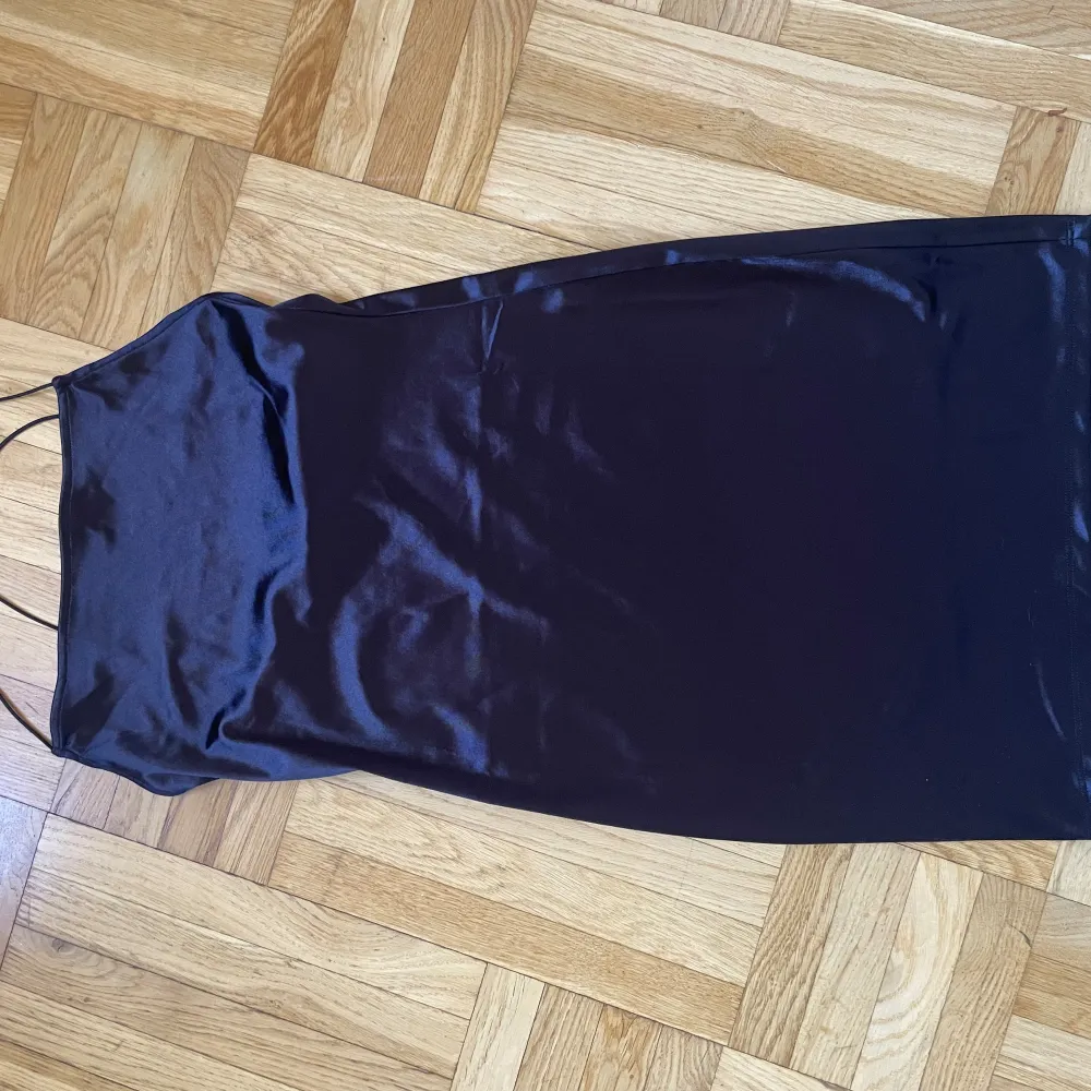 Kort klänning i svart glasigt tyg med smala axelband från H&M, stl M. Klänningar.
