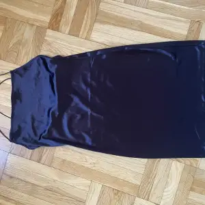 Kort klänning i svart glasigt tyg med smala axelband från H&M, stl M
