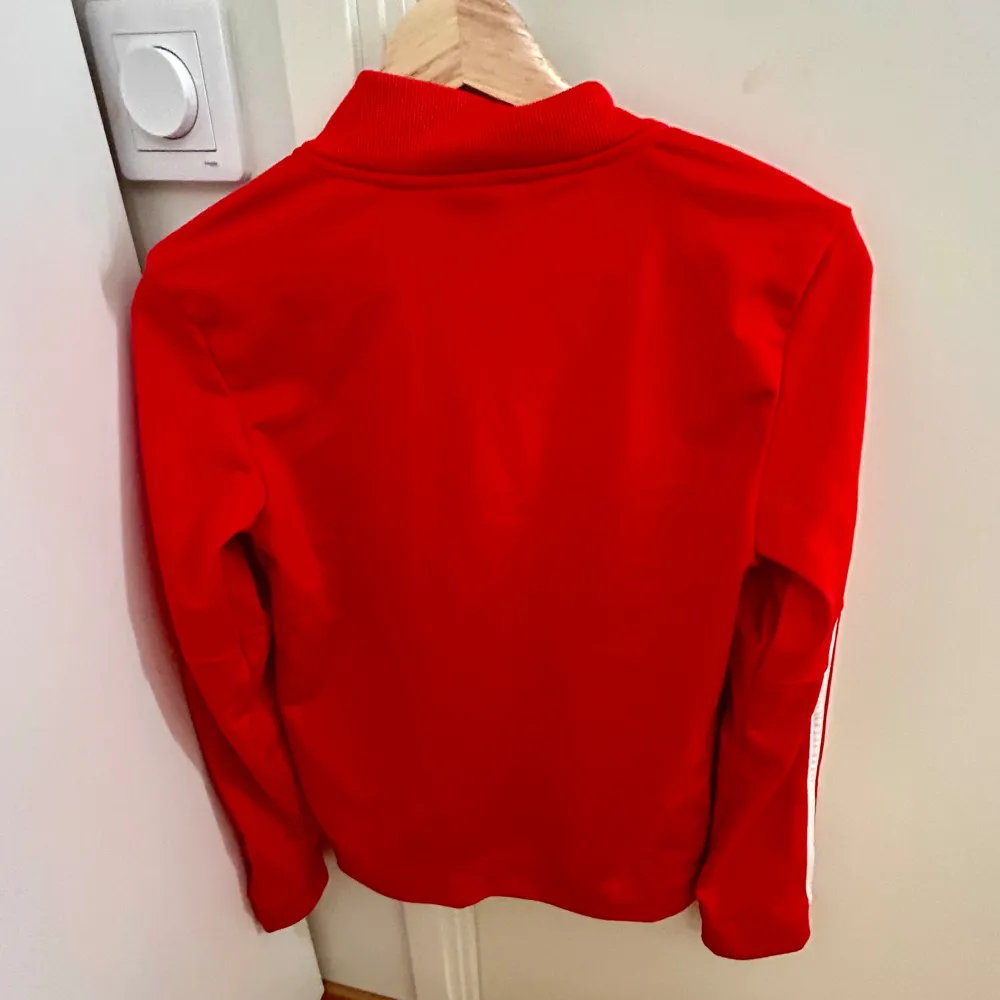 Säljer denna röda adidas zip-up tröjan som aldrig är använd. Det står storlek Xs men jag skulle säga att den är en S. Den är ganska stor på mig som brukar bära S/Xs. Skriv privat för frågor! . Tröjor & Koftor.