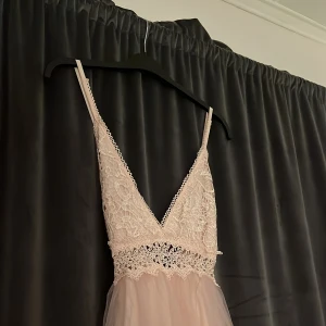 Rosa balklänning med slits - En oanvänd balklänning som är öppen i ryggen, överdelen är en fin spets som formar sig bra till kroppen. Jag är 168 och den faller fint ner till marken med 3cm. Säljer den för att den var förliten för mig.