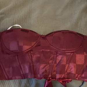 En vinröd korsett - Säljer en vinröd korsett med knytning där bak så man kan spänna in eller ut hur mycket man än vill. Knappt använd🩷