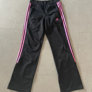 Adidas byxor - Jätte fina byxor från adidas med rosa detaljer. Har en liten defekt på knät men det syns inte alls🫶💕🤩tryck gärna på ”köp nu”!!!