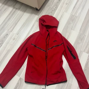 Röd Nike Tech Tröja - Röd Nike Tech tröja har haft den ett tag men fint skick och lite använt tröjan är strl XS. 
