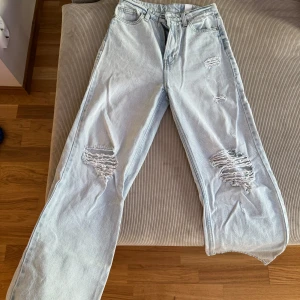 Slitna jeans - Snygga jeans med hög midja, utsvängda ben och slitningar. Använda men i mycket bra skick!