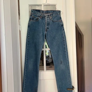 Levis straight vintage jeans 501 - Snygga klassiska Levis 501 i W 28, midjemått rakt över 34 cm och innerbenslängd 74 cm. En fläck där bak som ni ser men ej testat tvätta. Levis märket uppe där bak är även aningen slitet. 