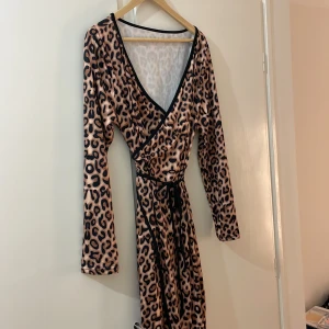 Leopardfärgad omlottklänning - Omlottklänning i leopardmönster. Oanvänd, lång, lätt stretchig